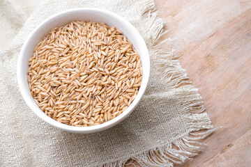 oat seeds in a round bowl isolated on wooden background top view