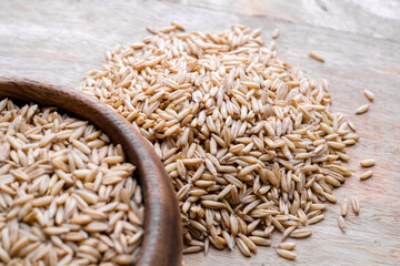 oat seeds in a wooden plate on wooden background top view. Closeup seeds