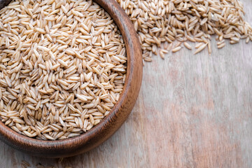 oat seeds in a wooden plate on wooden background top view. Closeup seeds