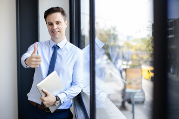 Fototapeta premium Portrait of Happy success businessman holding laptop gesture thumb up. Manager professional executive standing at office.