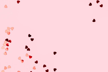 Metallic red confetti in a heart shape scattered on a pink background. Composition with copy space. - Powered by Adobe