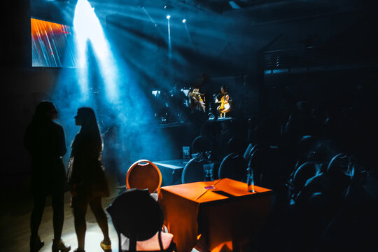 Two young girls dance to music of an orchestra in bright light of beams of the stage spotlights