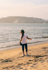 girl at the beach on a sunny afternoon using binoculars, walking and kicking the sand, Girl Looking at the beach through binoculars on a sunny afternoon, backlit, walking and smiling, kicking up the s