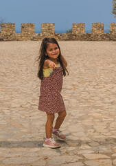 Fototapeta na wymiar girl posing in the old fortress, girl in a natural pose in a stone fortress, looking at the camera, smiling and moving