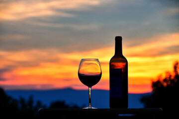 Silhouette of a glass of red wine and wine bottle at sunset with Virginia mountains in the...