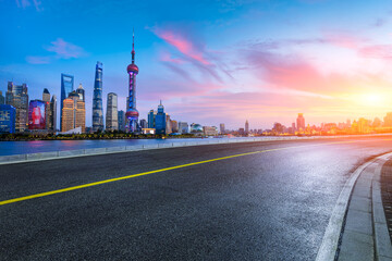 Asphalt road and city skyline with modern buildings at sunset in Shanghai, China.