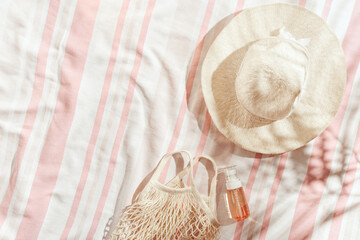 Summer Lifestyle flat lay with wide-brimmed sun hat, cosmetics products in mesh bag on stripes...