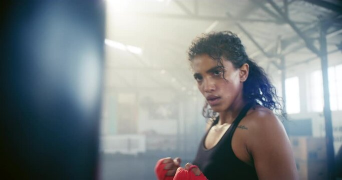Boxing, sweating and fight with woman in gym for martial arts, workout and strong. Focus, health and cardio with female boxer and punching bag in fitness center for training, exercise and performance