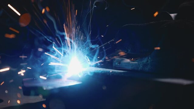 The man is welding. Welding with argon or electrode, using a welding machine. Sparks and flashes fly.