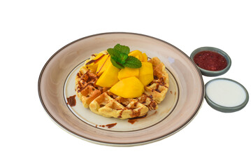 Belgium waffles with sliced mango on a plate with tropical topping and yogurt sauce  