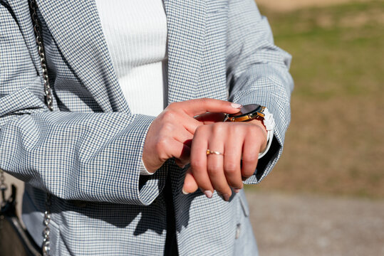 Unrecognizable woman touching wristwatch while standing in park