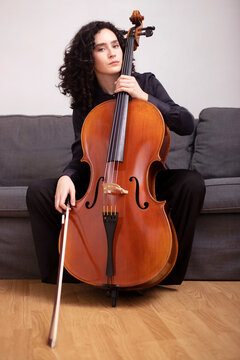 Female musician playing cello while sitting on sofa