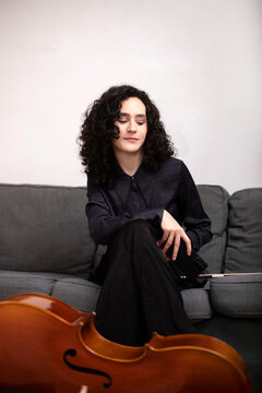 Positive woman with cello sitting on sofa