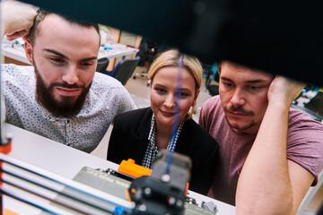 A group of colleagues working together in a robotics laboratory, focusing on the intricate fields of robotics and 3D printing. Showcase their dedication to innovation, as they engage in research