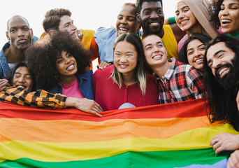 Crowd of multiracial people having fun together during LGBT pride parade outdoor - Diverse young friends from diverse cultures holding rainbow flag - obrazy, fototapety, plakaty