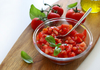 Concetto di cibo italiano. Pomodori freschi tagliati a pezzetti e conditi con origano, basilico e olio d'oliva per bruschette. Antipasto alimentare.