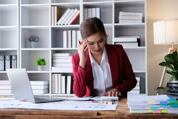 Portrait of tired young business Asian woman work with documents tax laptop computer in office. Sad, unhappy, Worried, Depression, or employee life stress concept