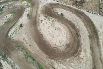 Drone aerial of a motocross race on a dirt curvy sport track. Aerial view of high-speed racing