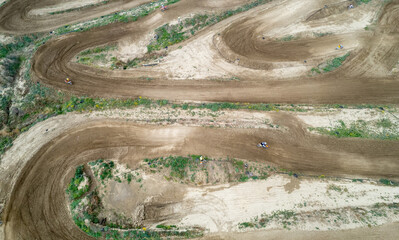 Drone aerial of a motocross race on a dirt curvy sport track. Aerial view of high-speed racing