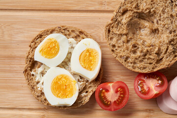 Sandwiches with tomatoes, eggs and mayonnaise on a wooden plate.