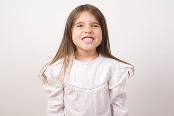 Cute charming little girl wearing white shirt over white background clenching teeth feeling excited or angry. 