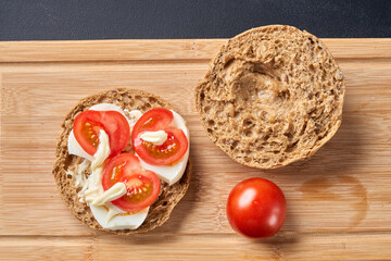 Sandwiches with tomatoes, eggs and mayonnaise on a wooden plate.