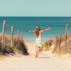 Happy woman with dress in sand dunes,  beautiful beach in atlantic ocean in France - obrazy, fototapety, plakaty