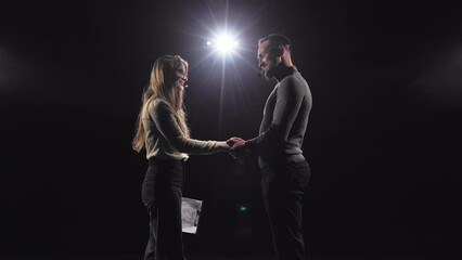 Side view of caucasian motivational mentors in headsets shaking hands for greeting each other on stage. Young man and woman in casual wear discussing their knowledge on business meeting.