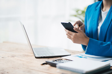 Close up view of businesswoman using smartphone while working at the office desk.