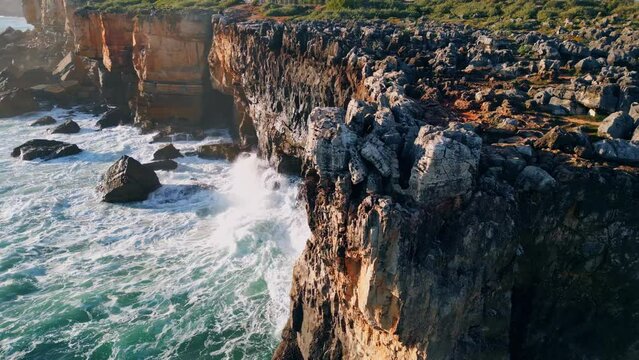 High rough coastal rock over powerful sea at sunny day. Drone volcanic cliffs