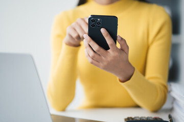 Close up view of businesswoman using smartphone while working at the office desk.