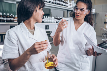 Two female chemistry scientists  doing experiments in the lab.	