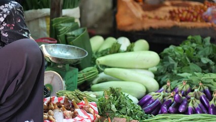 An Indonesian woman paying with cash money in tradtional market. Indonesian man paying on traditional market using cash money - Powered by Adobe