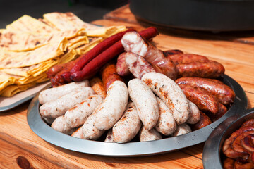 Set of appetizing fried grilled sausages on a wooden background. Oktoberfest food, pub concept. Street food to go.	