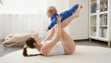 Happy laughing baby boy having fun with mother doing fitness exercises on floor. Family healthcare,...