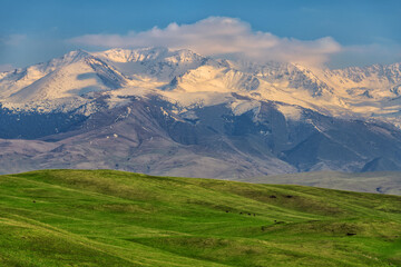 Picturesque alpine plateau and snow-covered peaks on a spring evening