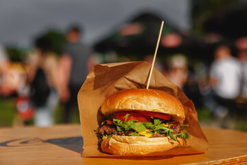 Hamburger at outdoor street food market festival in a park.