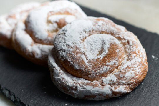 closeup of some ensaimadas with icing sugar on a slate table