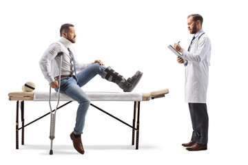 Man with an orthopedic boot and neck collar sitting on a therapy table and physical therapist...