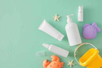 Child summer skincare idea. Top view flat lay mockup of cosmetic bottles, beach toys and starfish on teal background with empty area for text or logo