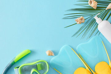 Summer adventure concept. Top view flat lay of diving mask with snorkel, flippers, cosmetic bottle, seashells and palm leaf on light blue background with space for text or logo