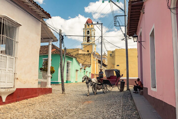 Fototapeta na wymiar Horse-drawn carriage in the alleys and historic districts of Trinidad with the San Francisco de Asis church