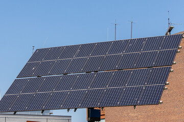 Black solar panels with red brick wall in daytime