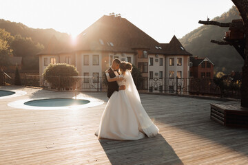 Wedding portrait. A groom in a black suit and a blonde bride dance a waltz against the background...