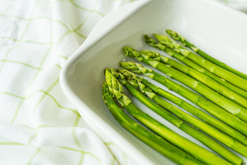 Green asparagus lies in a baking dish in the oven. Clean and wholesome food for health. Seasonal product. Healthy food concept.