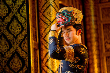 Fototapeta na wymiar Close up Asian man with traditional cloth relate to Khon or Thai classic masked with holding black monkey mask stand in front of windows of public building.
