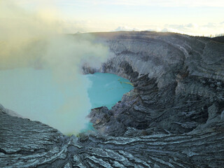 Wulkan Ijen z błękitnym jeziorem kwasu siarkowego w kraterze z którego wydobywa się płynna siarka i toksyczne opary gazu siarkowego - 603776796