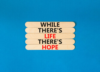 Life and hope symbol. Concept word While there is life there is hope on wooden stick. Beautiful blue table blue background. Business lifestyle life and hope concept. Copy space.