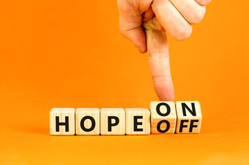 Hope on or off symbol. Businessman turns wooden cubes and changes word Hope off to Hope on. Beautiful orange table orange background. Business and hope on or off concept. Copy space.