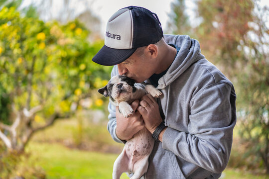 Handsome man hugging and kissing a cute french bulldog puppy.  Copy space